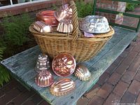 Large wicker picnic basket with handle and double lids, visible breaks on handle and lids, placed on outdoor wooden bench.