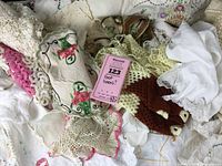Mixed assortment of vintage linens showing variety of lace, embroidery, and ruffled eyelets in a pile