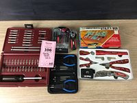 Overall view of all tools in the lot showing four distinct tool groups including red-handled Snap-on multi-tool set, SKIL mini screwdriver set, hex bits and small pliers, and a compartmented utility box.