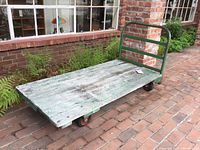 Full angled view of the industrial flatbed trolley showing the wooden deck, metal frame, and wheels.