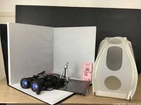 Photo showing the open folding backdrop with three cloths, two black photography lights, small tripod, plastic light box, and product shot aids flyer