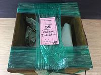 Top view of the vintage wooden Reliable egg carrier box wrapped in green plastic wrap, partially open with packing paper inside.