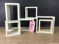 Five white wall display cubes arranged with visible sizes and shapes against a dark background.