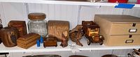 Photo of assorted wood craft items on a white shelf including various boxes, a glass jar with wood lid, model car, driftwood pieces, and a wooden music box.