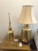 Two etched brass canister lamps on small side table, one with fabric shade, smaller lamp without shade