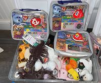 Wide shot showing a bin with assorted TY Beanie Babies plush toys and three clear vinyl Platinum Membership kits containing plush bears and collector items