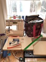 Serger on table with tote bag, manual, extension table and foot pedal visible
