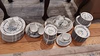 Wide view of stacked plates, cups, saucers and serving dishes showing a large set of matching Noritake Shangri-La porcelain dinnerware and serveware.