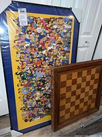 Photo displaying the Simpsons poster leaning against a door with the woodcraft chess board resting nearby.