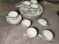 Multiple Wedgwood teacups and saucers with plates stacked under them, all showing delicate Kutani style crane and floral decoration.