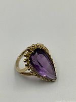 Front three-quarter view showing large pear-shaped amethyst and gold bead bezel