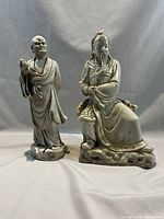 Both statuettes shown side by side on neutral background