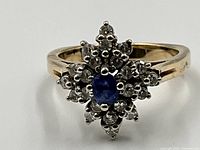 Front view of ring showing blue sapphire center and surrounding diamonds