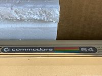 Close-up of the Commodore 64 logo and badge on the computer unit.