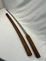 Katana sword unsheathed next to wooden scabbard