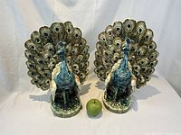 Full view of both ceramic peacock vases with green apple for scale