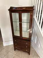 Front view showing glass front upper cabinet, two glass doors and lower drawers