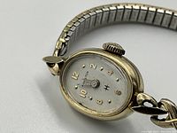 Close-up of oval white dial showing gold Arabic numerals, dot markers and Hamilton logo