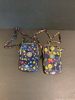 Front view of two mini pouches with star and animal prints, laid side by side showing logo, shape, and straps.