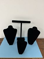 Four black velvet jewelry stands: two large busts, one small bust, and one horizontal bar stand