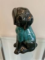 Front view of the Blue Mountain Pottery large dog figurine showing glossy black and turquoise glaze with detailed face and paws.