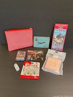 Photo showing entire lot including pink zippered pouch, Player's tin, Willie Nelson CD, cosmetic sponges, candle wax cubes, clear bulbs, earbuds, and Prince Edward County travel map.