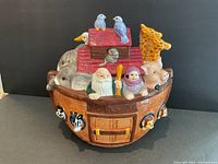 Front-angle photo showing Noah and his wife along with surrounding animal figures and the red roof lid with two blue birds on top.