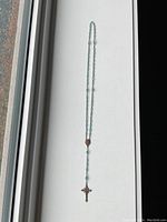 Full length photo of the vintage light blue glass bead rosary laid flat showing length and bead details.