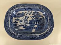 Top view of the Blue Willow platter showing the detailed traditional blue and white pattern with buildings, boats, and trees.
