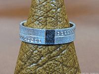 Front view of the milled sterling silver ring with black square accent and stamped indentations on the band.