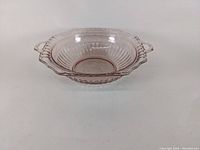 Side angle view of the pink depression glass berry bowl showing its shape and handles.