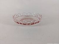 Side view of pink depression glass shallow bowl showing scalloped looped edge and shiny surface in excellent condition.