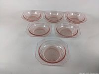 Top view of six pink Depression glass cereal bowls arranged in two rows of three.