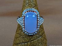 Front view of sterling silver ring featuring milky amethyst center stone and halo of clear accent stones.