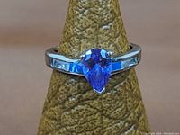 Front view showing pear-shaped purple amethyst stone set in sterling silver ring on display cone.