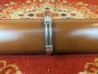 Side view of sterling silver double-band latching bangle bracelet showing latch mechanism and smooth polished finish.