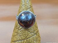 Front view of sterling silver ring with reddish-brown round cabochon stone on ring display cone.
