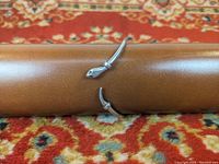 Sterling silver snake bracelet displayed on a brown cushion with a patterned red carpet background. Shows the snake head and tail ends.