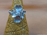 Front view of sterling silver dogwood flower ring displaying detailed petals and flower center.