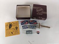 Top-down photo showing Schick shaver box, Gem razor, five packs of razor blades in vintage packaging from Domino, Coaster, Ingersoll, and Treet, and an FDR re-election campaign pin.