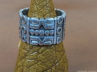 Front side view of a wide sterling silver ring with a geometric modernist/brutalist pattern