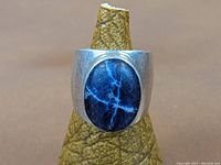 Front view of the wide sterling silver ring with an oval lapis lazuli stone set in the center.