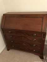 Front view of closed desk showing exterior wood finish, brass hardware and overall condition