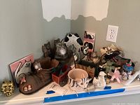 Overview of various cat figurines, decorative items, and cat-themed tile and notepads arranged on a surface.