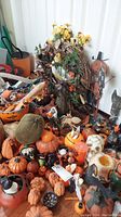 Overview of numerous Halloween decorations including pumpkins, candles, and figurines arranged on a table.