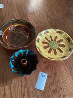 Top view of all three pottery pieces showing floral and blue glaze designs arranged on wood floor.