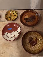 Overhead shot of four redware plates on plywood surface