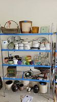 Full view of shelving unit with items on upper shelves including enamelware canisters and bowls