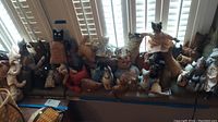 Overview of 18 handmade cloth cats displayed on bench