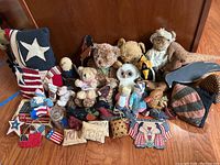 Wide view showing various Americana pillows with star and flag motifs, stuffed animals including teddy bears, owl, and cats, and small patriotic fabric items.